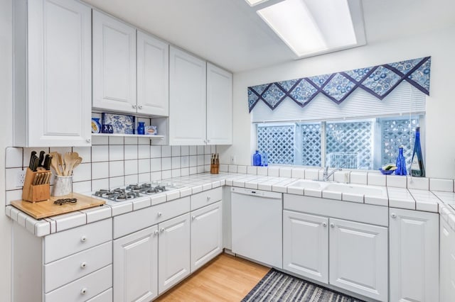 kitchen featuring light hardwood / wood-style floors, white appliances, backsplash, white cabinets, and tile countertops