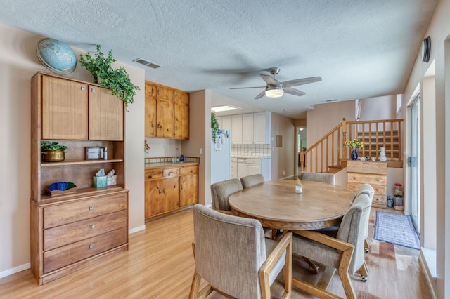 dining area featuring ceiling fan, a textured ceiling, and light wood-type flooring