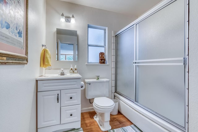 full bathroom featuring toilet, combined bath / shower with glass door, vanity, and hardwood / wood-style flooring