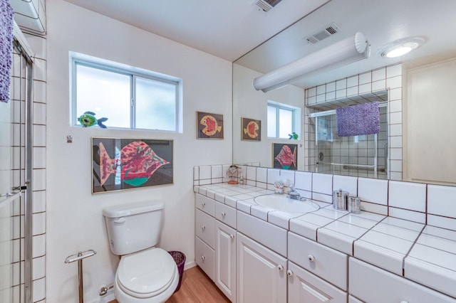 bathroom with a shower with shower door, hardwood / wood-style floors, toilet, and vanity