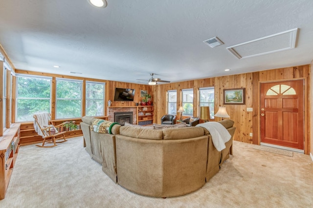 living room featuring wooden walls, plenty of natural light, a fireplace, and light carpet