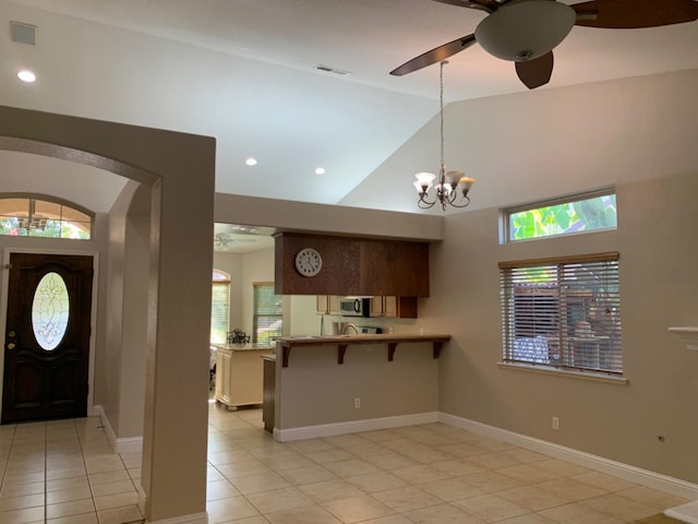 kitchen featuring kitchen peninsula, a healthy amount of sunlight, a kitchen breakfast bar, and light tile patterned floors