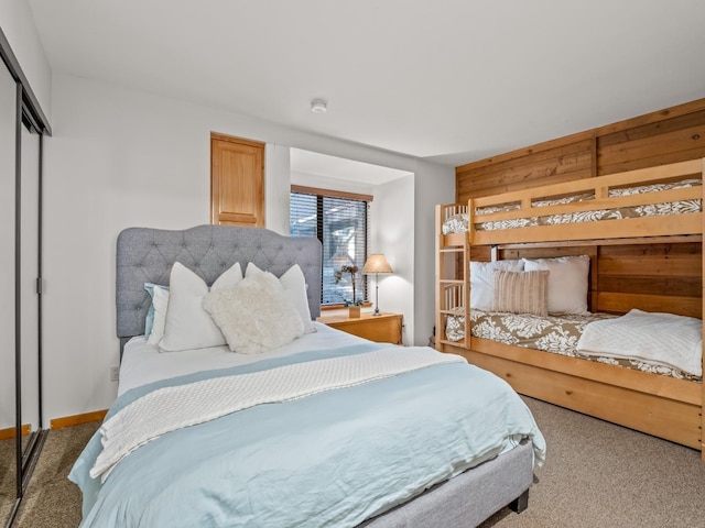 carpeted bedroom with a closet and wood walls