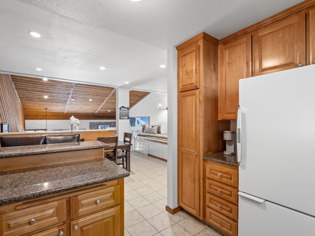 kitchen featuring light tile patterned floors, brown cabinetry, recessed lighting, and freestanding refrigerator