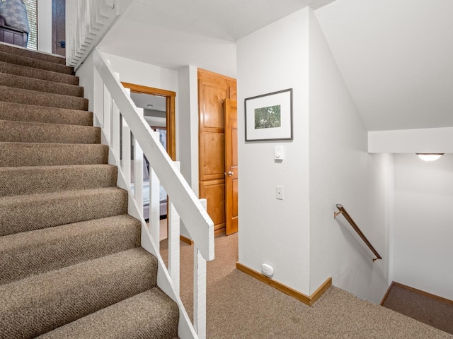 stairs featuring baseboards, lofted ceiling, and carpet flooring