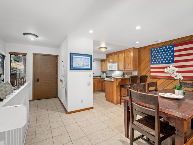 kitchen with white microwave, a peninsula, recessed lighting, light countertops, and range with electric stovetop