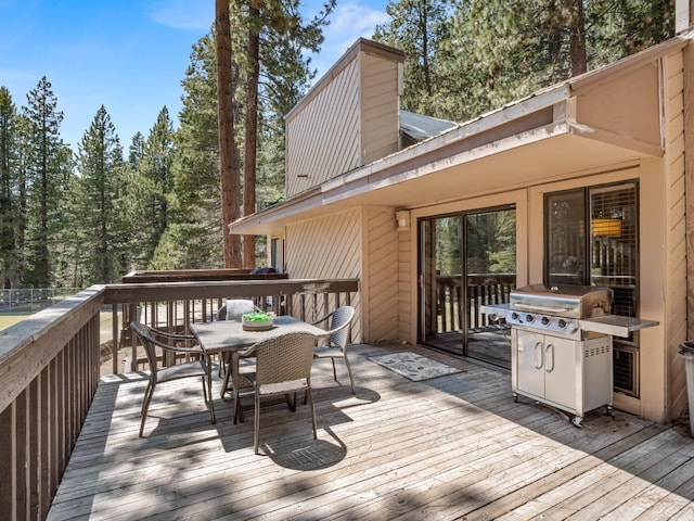 wooden deck with outdoor dining area and a grill