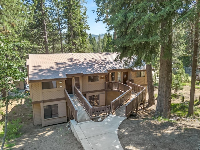 chalet / cabin with stairway, metal roof, and a deck