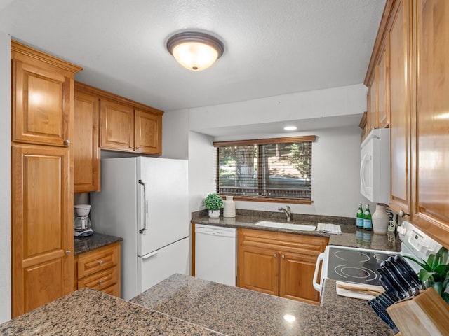 kitchen featuring brown cabinets, white appliances, and a sink