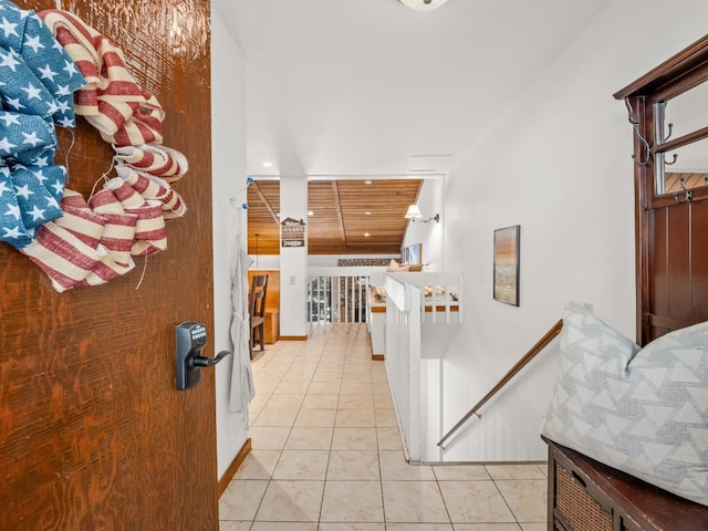 hallway featuring an upstairs landing, wood ceiling, baseboards, and light tile patterned flooring