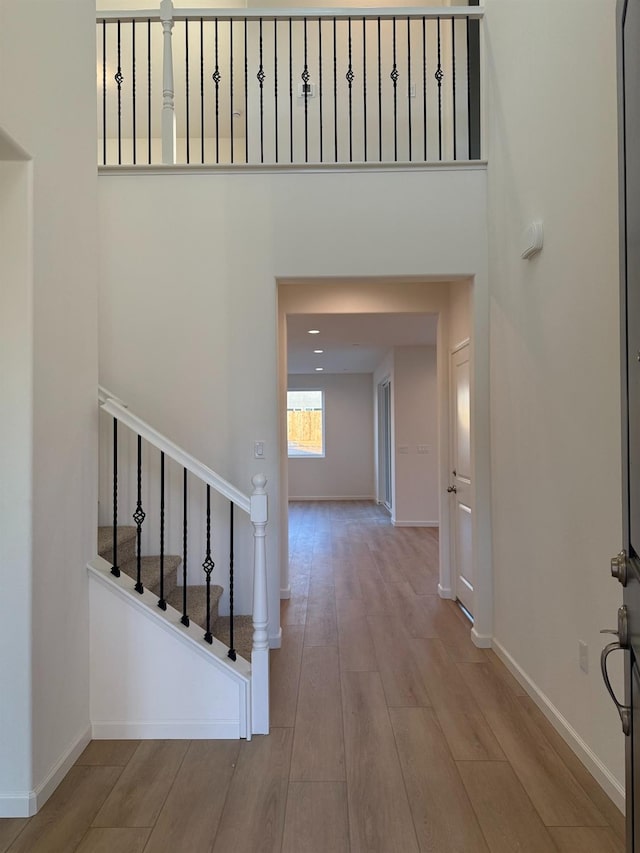 entryway with light hardwood / wood-style flooring and a towering ceiling