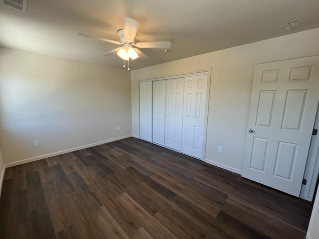 unfurnished bedroom with dark wood-type flooring, ceiling fan, and a closet