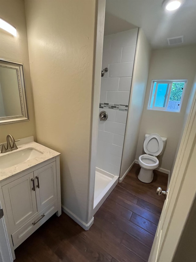 bathroom featuring vanity, walk in shower, wood-type flooring, and toilet