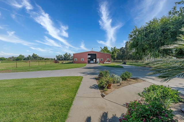 view of front of house with an outdoor structure, a front yard, and a rural view