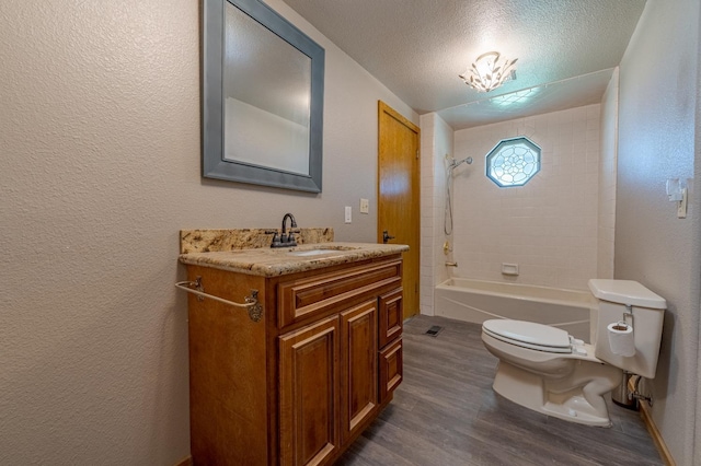 full bathroom with hardwood / wood-style flooring, vanity, tiled shower / bath combo, toilet, and a textured ceiling