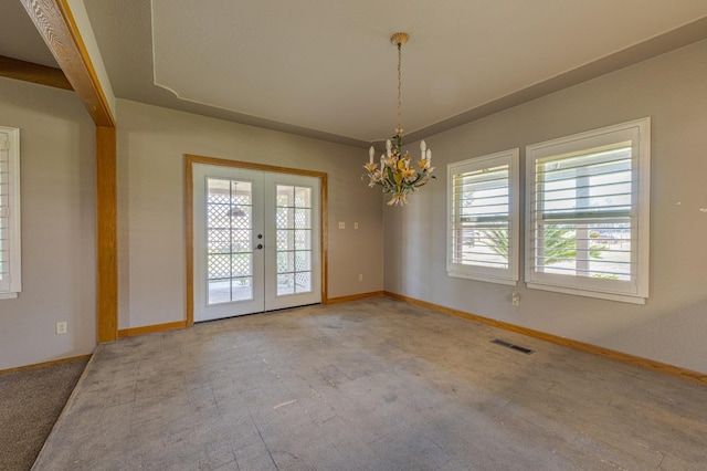 carpeted spare room featuring french doors and a chandelier