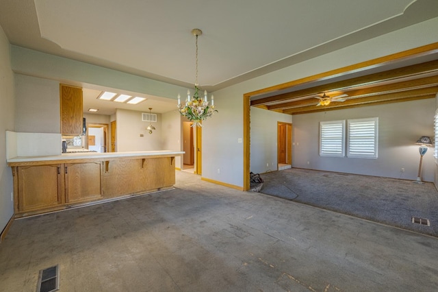 unfurnished dining area with beamed ceiling, ceiling fan with notable chandelier, and light colored carpet