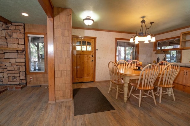 dining area featuring an inviting chandelier, dark wood-type flooring, and ornamental molding