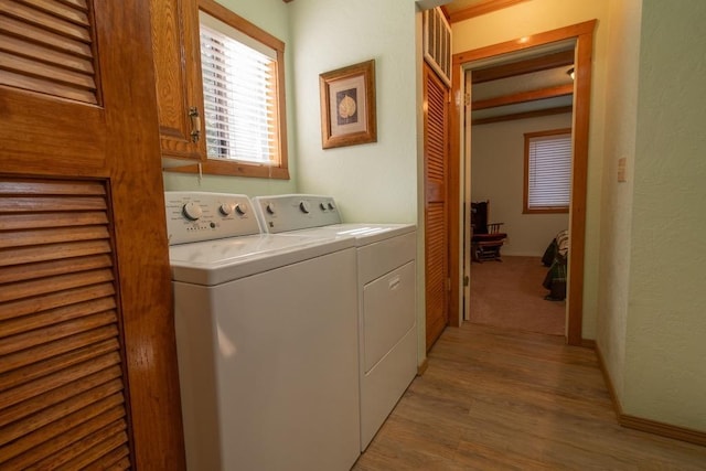 washroom featuring light hardwood / wood-style flooring, washer and clothes dryer, and cabinets