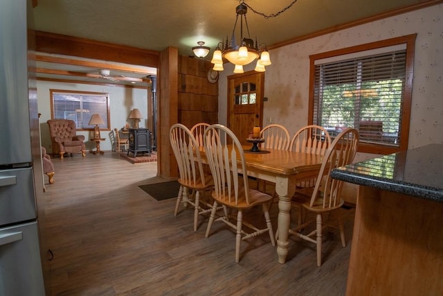 dining room featuring crown molding, a notable chandelier, dark hardwood / wood-style floors, and a wood stove