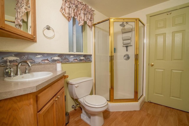 bathroom with wood-type flooring, toilet, a shower with door, and vanity