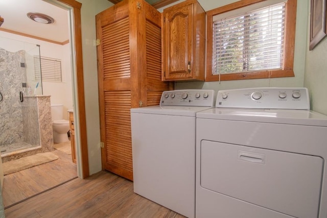 clothes washing area with cabinets, light hardwood / wood-style floors, and washer and dryer