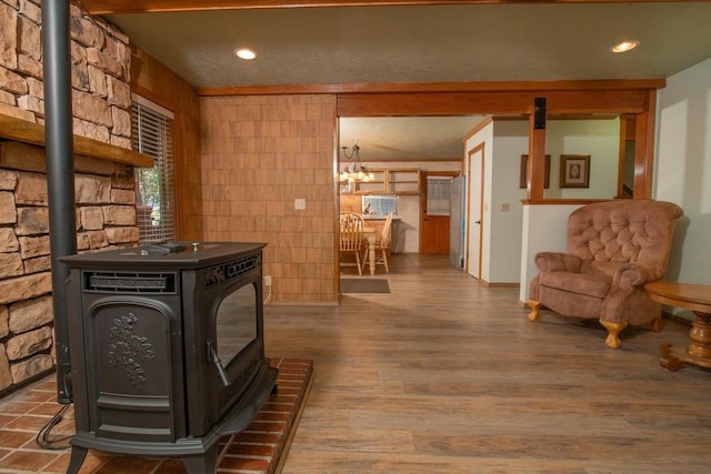 interior space featuring wood-type flooring, a chandelier, and a wood stove