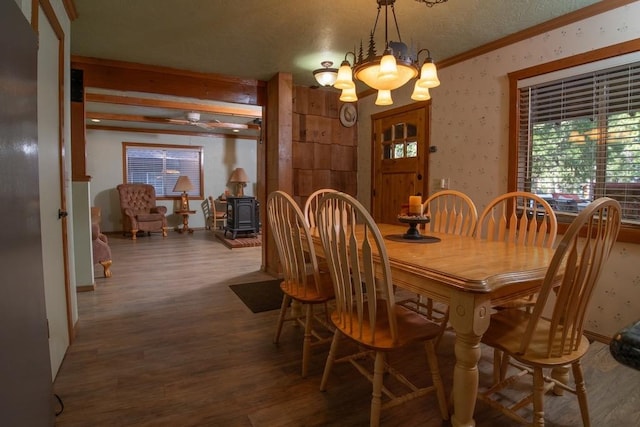 dining area featuring ornamental molding, a wood stove, an inviting chandelier, and dark hardwood / wood-style flooring