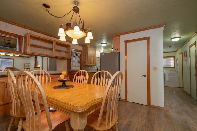 dining area featuring hardwood / wood-style flooring, ornamental molding, and washer / dryer