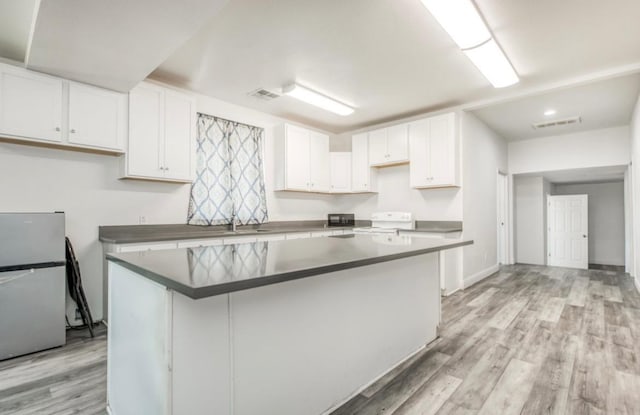 12647 E Clarkson Ave, Kingsburg, CA 93631 - kitchen with range, a center island, light hardwood / wood-style flooring, stainless steel fridge, and white cabinets