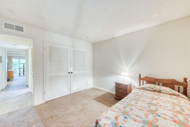 carpeted bedroom with a closet and a textured ceiling