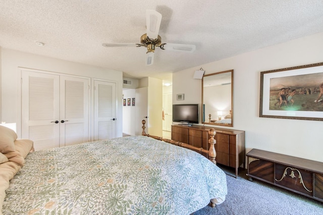 carpeted bedroom with two closets, a textured ceiling, and ceiling fan