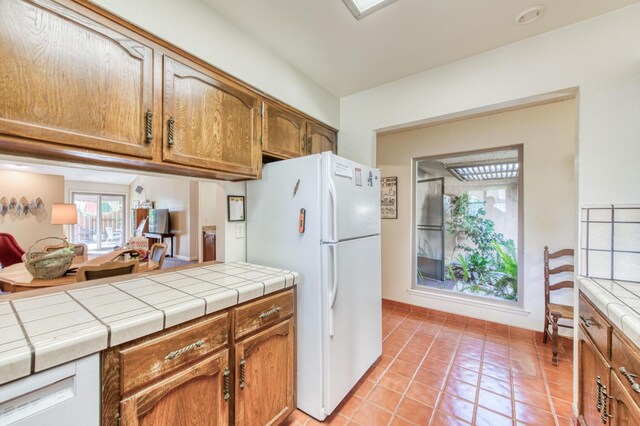 kitchen featuring tile countertops, light tile patterned floors, and white appliances