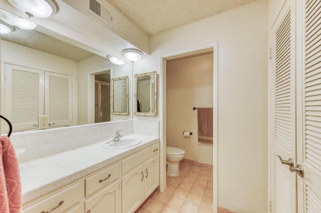 bathroom featuring vanity, tile patterned flooring, toilet, and a textured ceiling