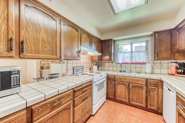 kitchen with decorative backsplash, tile countertops, white appliances, and light tile patterned floors