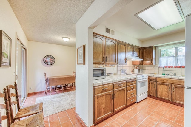 kitchen featuring white range with electric cooktop, decorative backsplash, tile countertops, and light tile patterned floors