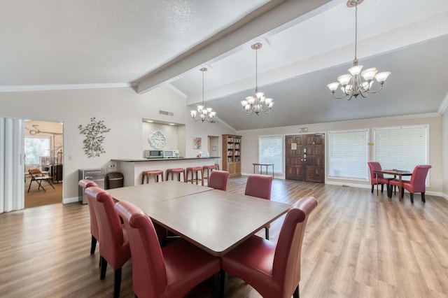 dining space featuring beamed ceiling, hardwood / wood-style floors, a wealth of natural light, and an inviting chandelier