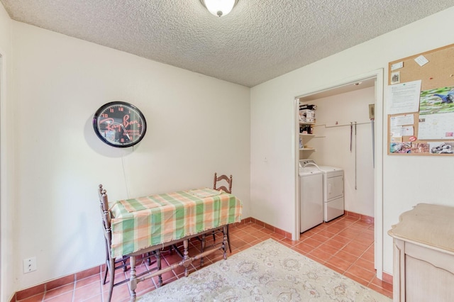 bedroom with a textured ceiling, separate washer and dryer, and light tile patterned floors