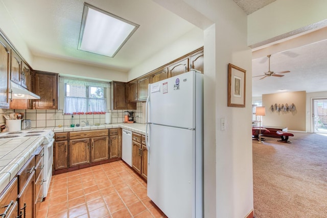 kitchen with plenty of natural light, decorative backsplash, white appliances, and light colored carpet