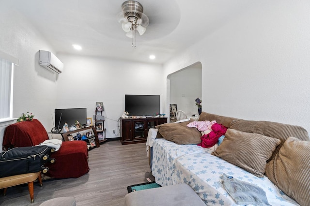 living room with light wood-type flooring, an AC wall unit, and ceiling fan