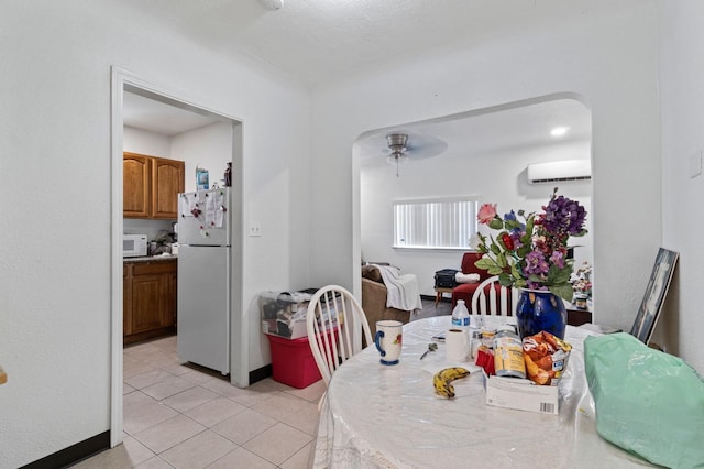 dining space featuring ceiling fan, light tile patterned floors, and a wall mounted air conditioner