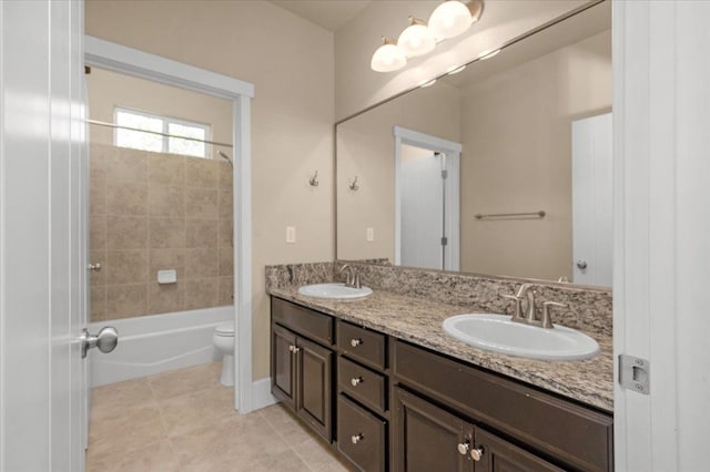 full bathroom featuring dual vanity, tiled shower / bath, tile patterned floors, and toilet