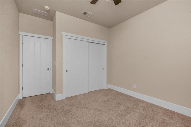 unfurnished bedroom featuring light colored carpet, a closet, and ceiling fan