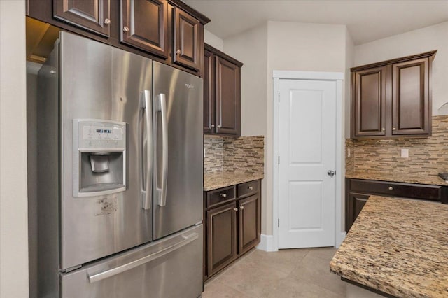 kitchen with dark brown cabinets, light tile patterned floors, stainless steel refrigerator with ice dispenser, and decorative backsplash