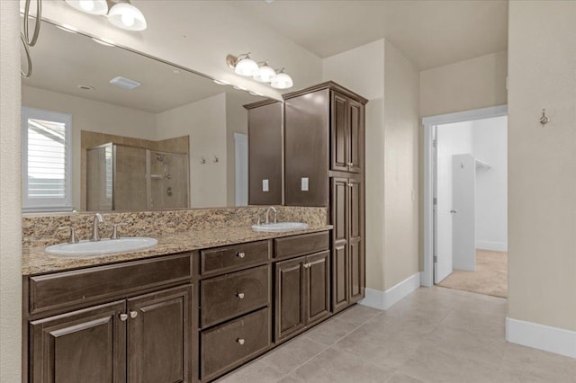 bathroom featuring a shower with door, tile patterned flooring, and dual bowl vanity