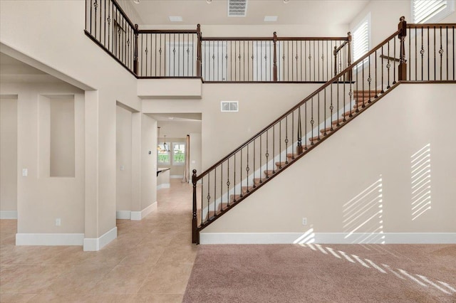 stairway with tile patterned floors and a high ceiling