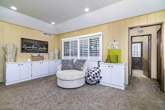 sitting room featuring wood walls, a textured ceiling, and carpet flooring