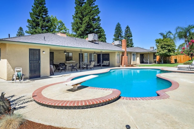 view of swimming pool with a patio area, a diving board, and ceiling fan