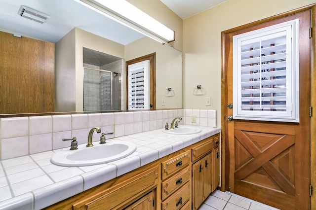 bathroom featuring vanity, backsplash, a shower with door, and tile patterned floors