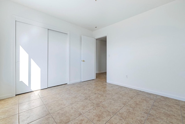 unfurnished bedroom with light tile patterned flooring and a closet